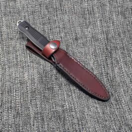 A Handmade Leather Sheath for the Benchmade Fixed Infidel laying on top of a gray cloth.