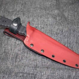 A Kydex sheathed TOPS Wild Pig Hunter knife laying on a gray surface.