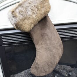 a stocking hanging from a fireplace with a furry tail.