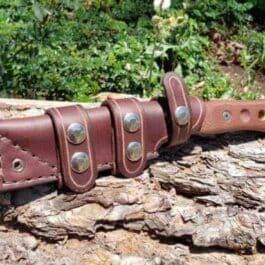 A Handmade Leather Scout Sheath For The TOPS Fieldcraft Knife sitting on top of a tree stump.