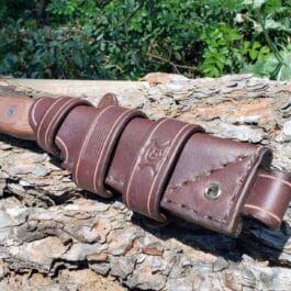 A handmade leather Scout sheath for the TOPS Fieldcraft Knife on top of a tree.