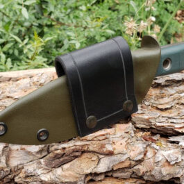 A Scout Style Benchmade Bushcrafter Sheath Style 2 sitting on top of a tree trunk.