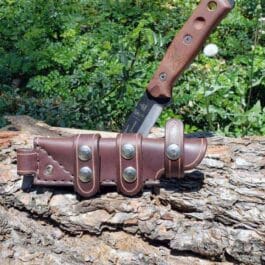A Handmade Leather Scout Sheath For The TOPS Fieldcraft Knife sitting on top of a tree stump.