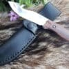 A Vertical Leather Sheath For The Benchmade Saddle Mountain Skinner is laying on top of a fur.
