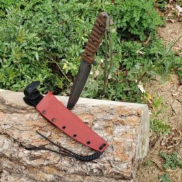 The Kydex Sheath for the TOPS Wild Pig Hunter is laying on top of a rock.