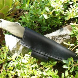 a knife is laying on a rock in the bushes.