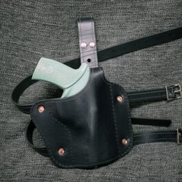A black Handmade Leather Thigh Holster with a light green handle.