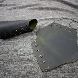 A pair of Soft Leather Mirkwood Vambraces sitting on top of a gray blanket.