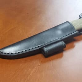 a knife with a leather sheath on a wooden table.