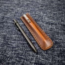 A Leather Pen Pocket Slip sitting on a blue cloth.