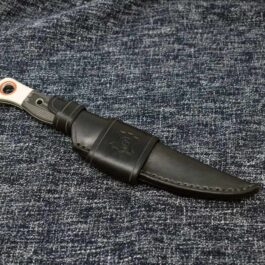 a black knife with a white handle on a blue cloth.