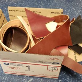 A box of scrap leather sitting on a table.
