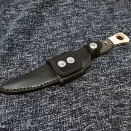 a knife with a leather sheath on a blue cloth.