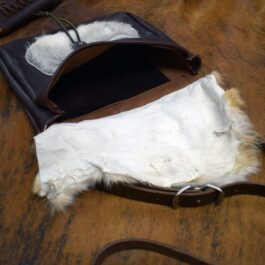 An Eastern legend Satchel with white fur inside of it.