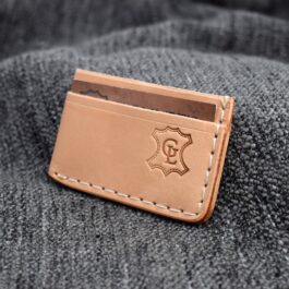 a brown leather wallet sitting on top of a gray blanket.