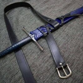 A blue and black Custom Wood Core Scabbard laying on the ground.