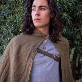 A man in a Linen Hooded Cloak standing in front of a bush.