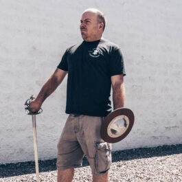 a very handsome man holding a sword and buckler