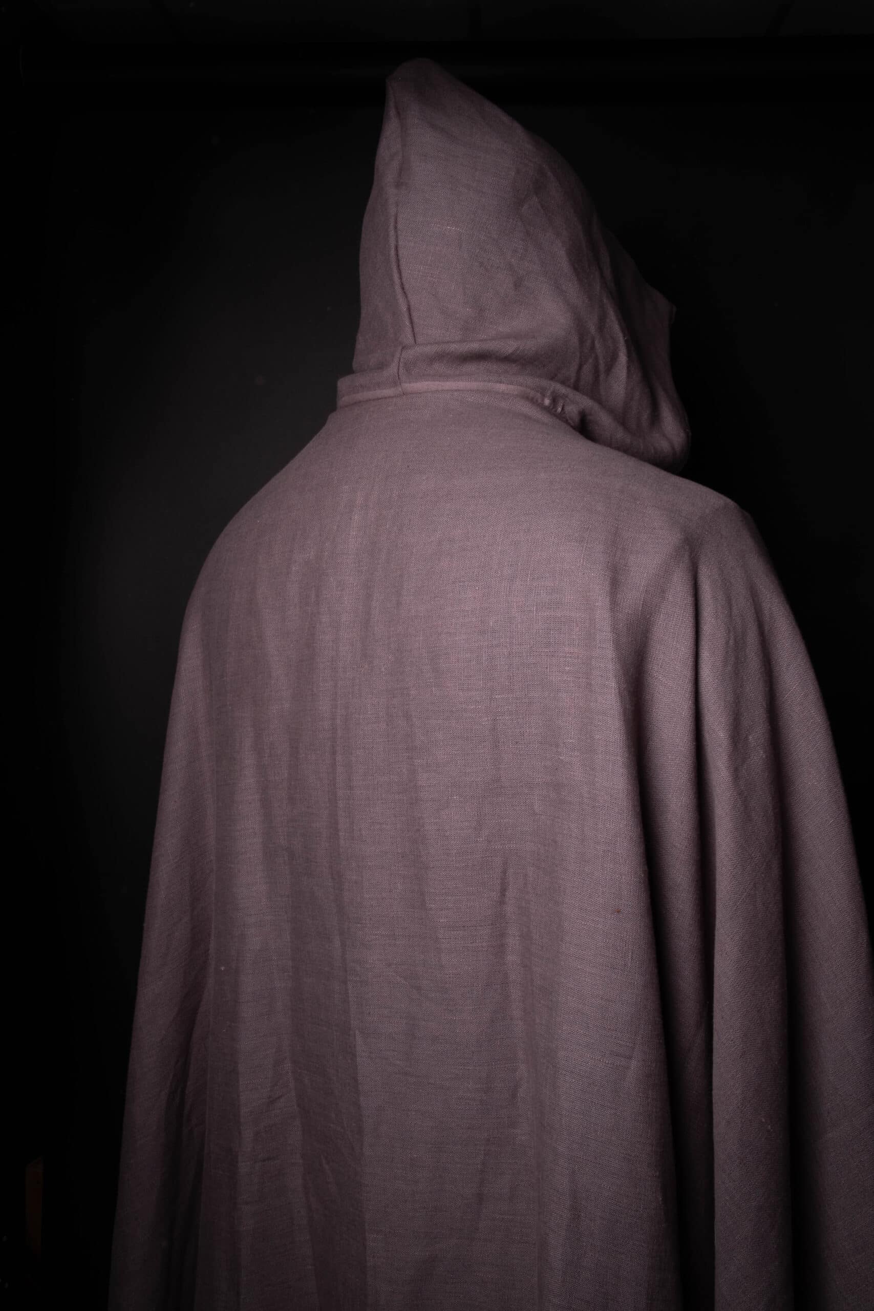 a person wearing a Wool Hooded Cloak in a dark room.