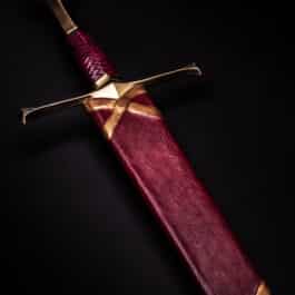 A red and gold sword in a Custom Wood Core Scabbard on a black background.