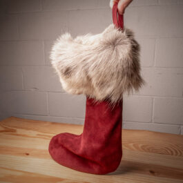 a red leather christmas stocking on a wooden table