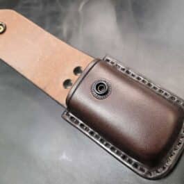 A molded leather multi tool pouch with a hole in the center.