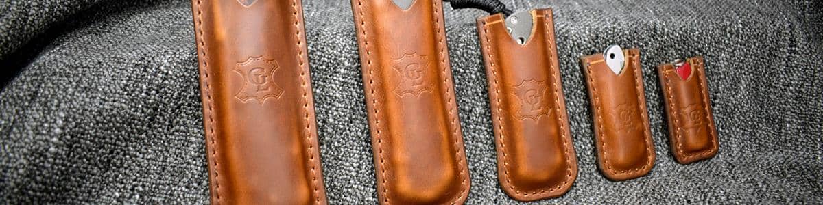 a group of leather knives sitting on top of a gray jacket.