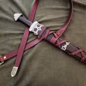 a leather sword laying on top of a bed.