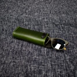a Handmade Leather Glasses Case laying on top of a gray cloth.