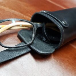 A Handmade Leather Glasses Case sitting on top of a wooden table.