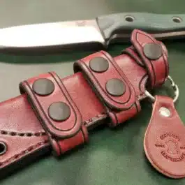 A Scout Style Leather Sheath for the Benchmade Bushcrafter attached to a knife.
