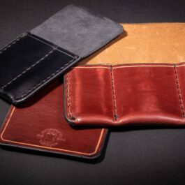 A couple of Handmade Leather 2 Slot Pocket Organizers sitting on top of a table.