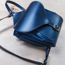 A Leather Cinch Top Backpack sitting on top of a wooden table.