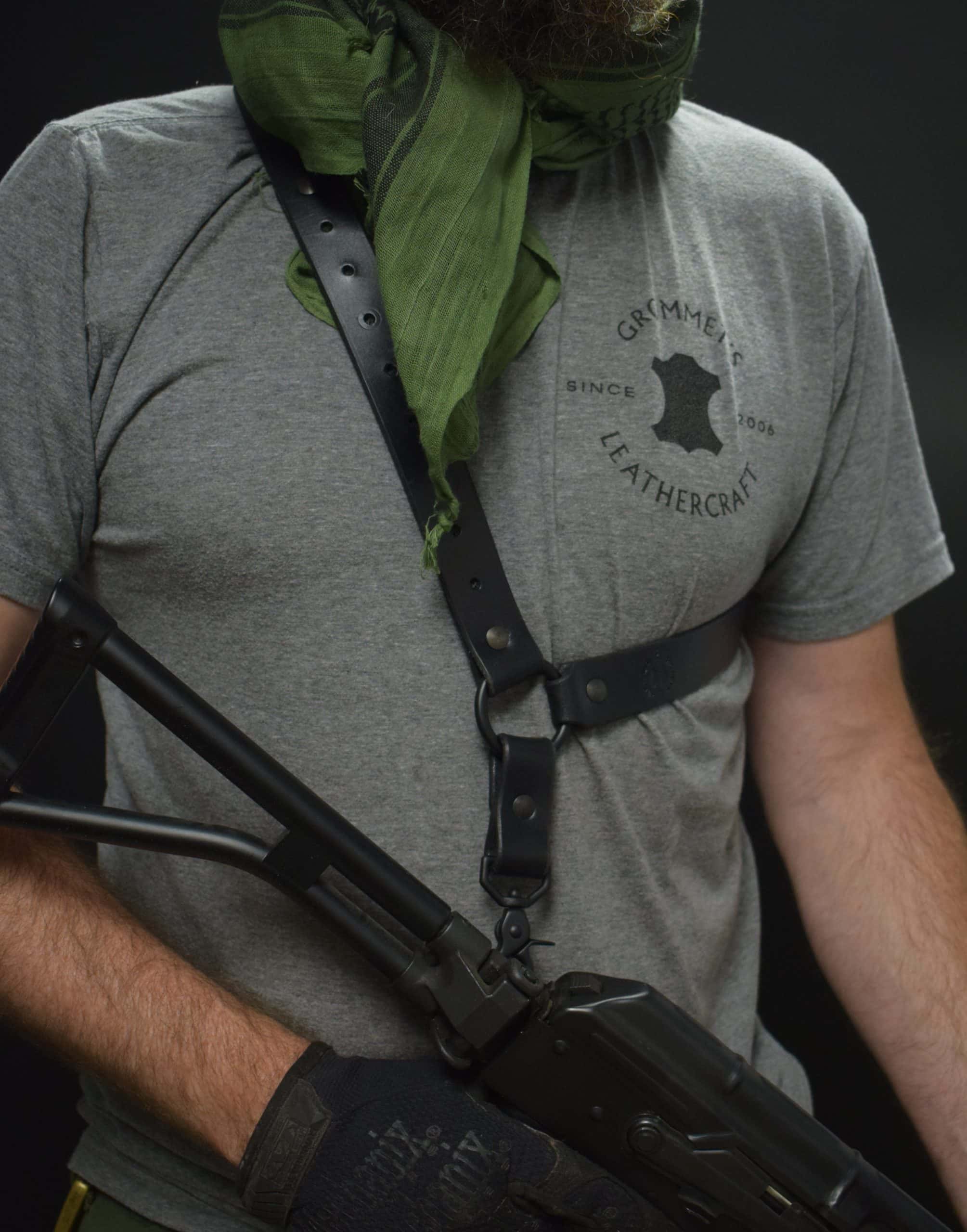 A man wearing a grey shirt and gloves with a black leather single point sling - Grommet's Leathercraft - renaissance clothing - renaissance art clothing - renaissance era clothing - leathercraft supplies - leathercraft accessories - leathercraft store near me - quality leather craft