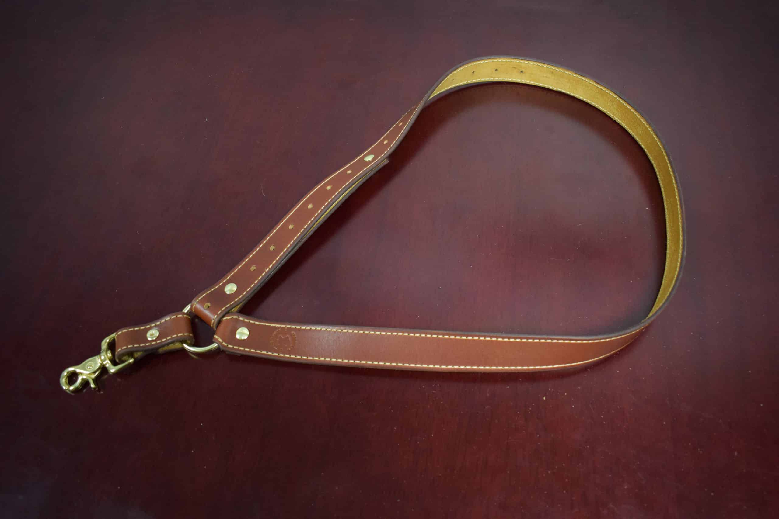 One brown leather single point sling laid on a wooden table - Grommet's Leathercraft - renaissance clothing - renaissance art clothing - renaissance era clothing - leathercraft supplies - leathercraft accessories - leathercraft store near me - quality leather craft