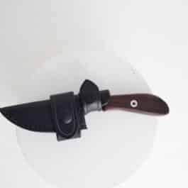 A Leather Scout Sheath for the White River Knives Backpacker/ Caper with a black handle on a white plate.
