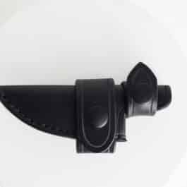 A Leather Scout Sheath for the White River Knives Backpacker/ Caper on a white plate.