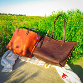 a bison and horween tote laying next to each other on a picnic blanket
