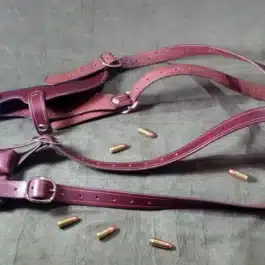 A shoulder holster for full size 1911s laying on a bed.