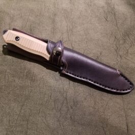 a Handmade Leather Sheath for the Benchmade Nimravus/Protagonist that is laying on a table.