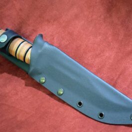 A Kydex sheath for the Ka Bar Fighting Knife that is laying on a red surface.
