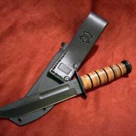 A Kydex Sheath for the Ka Bar Fighting Knife laying on top of a red blanket.