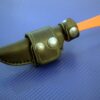 A handmade leather sheath for the Benchmade Altitude with two metal balls in it.