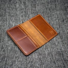 A Handmade Leather Passport Wallet sitting on top of a gray cloth.