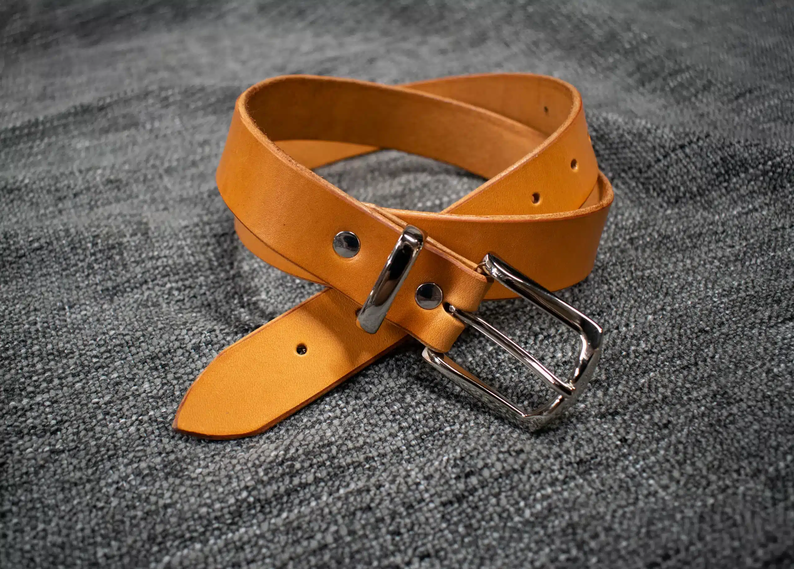 A handmade leather dress belt with a metal buckle.