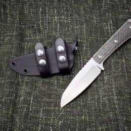 A Horizontal Kydex Sheath for the Chris Reeve Nyala laying on top of a green cloth.