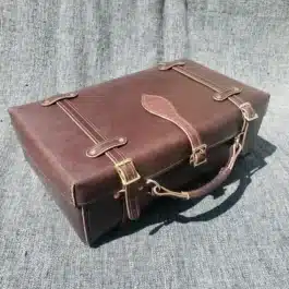 A Handmade Leather Suitcase sitting on top of a couch.
