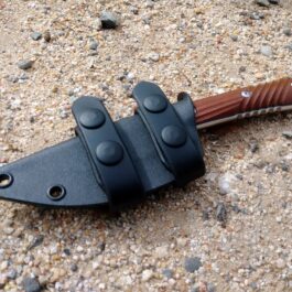 A Horizontal Kydex Sheath for the Chris Reeve Nyala that is laying on the ground.