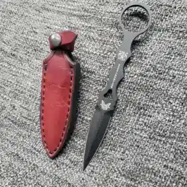 a Handmade leather Sheath for the Benchmade SOCP Dagger sitting next to a red leather case.