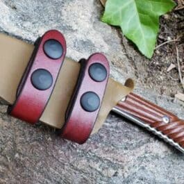 A Horizontal Kydex Sheath for the Chris Reeve Nyala with two holes on it laying on a rock.